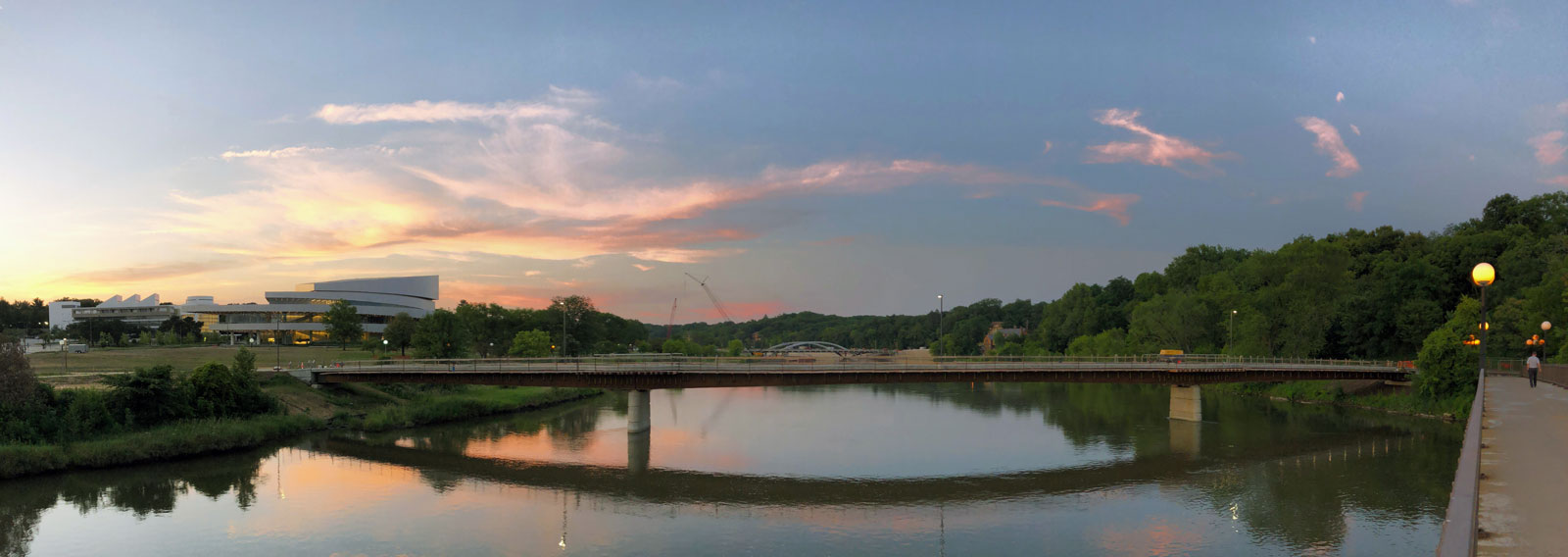 Aerial view of the Hancher Footbridge spanning the Iowa River, featuring cantilevered overlooks, cable railings, and a curving concrete deck.